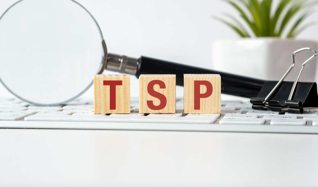 TSP Report November a magnifying glass is on a table with a keyboard and a stack of wooden blocks. the blocks spell out the word tps on the keyboardks